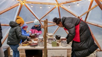 Une femme prépare un plat avec 3 enfants