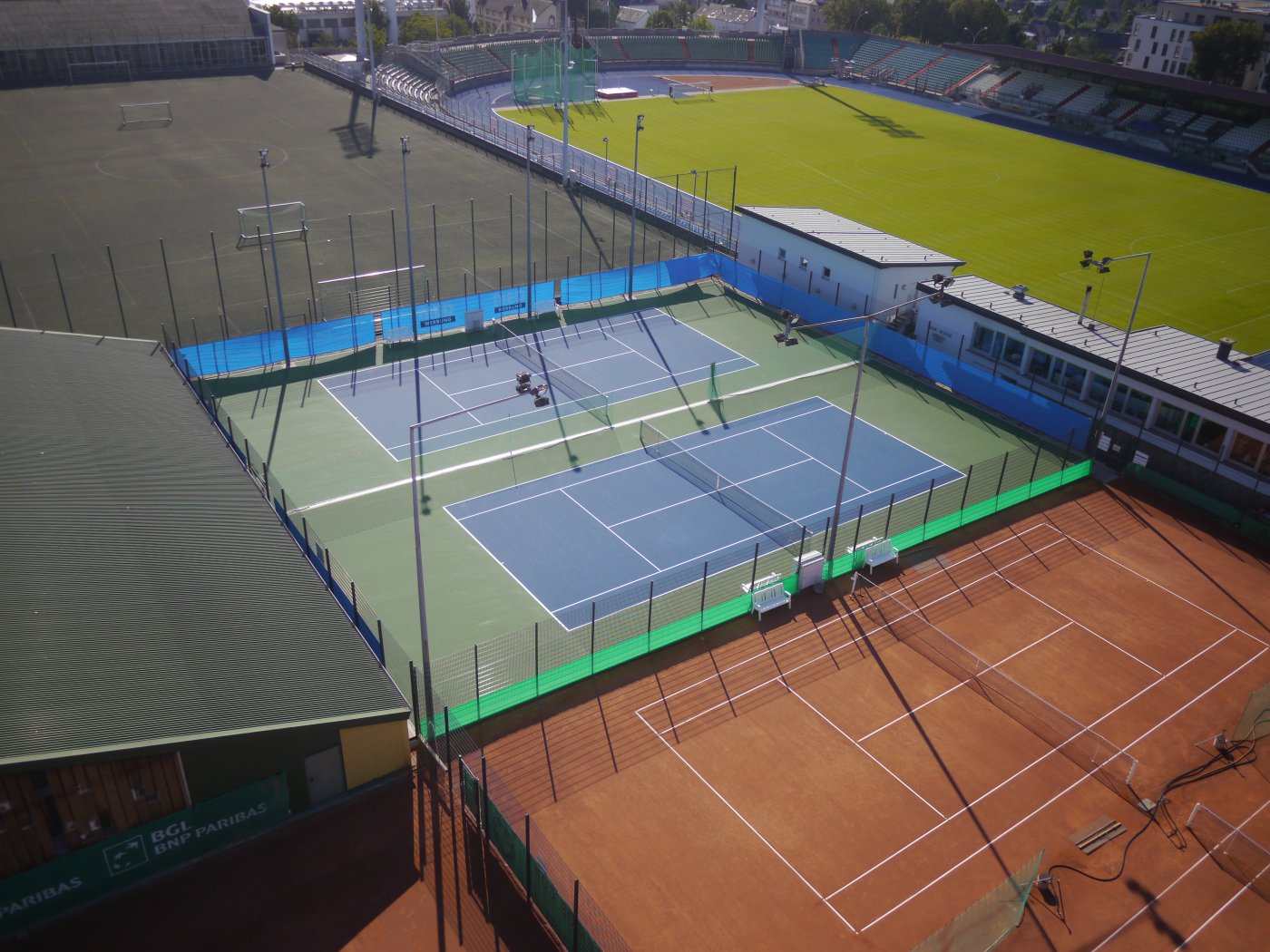 vue plongeante sur le hall de tennis et les terrains de tennis synthétiques et en terre battue du Stade Josy Barthel