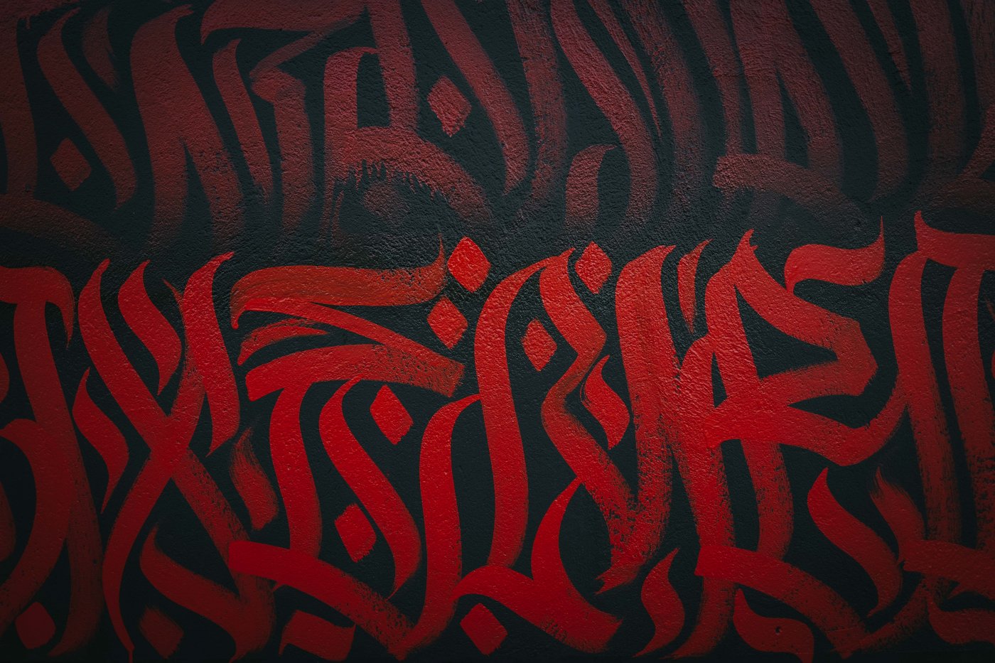 L'artiste REID entrain de peindre LE MUR avec un pinceau utilisant une couleur rouge.