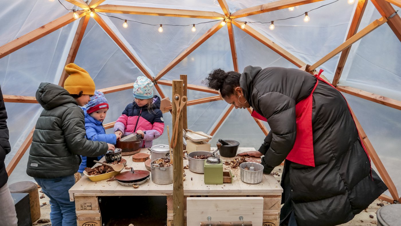 Une femme prépare un plat avec 3 enfants