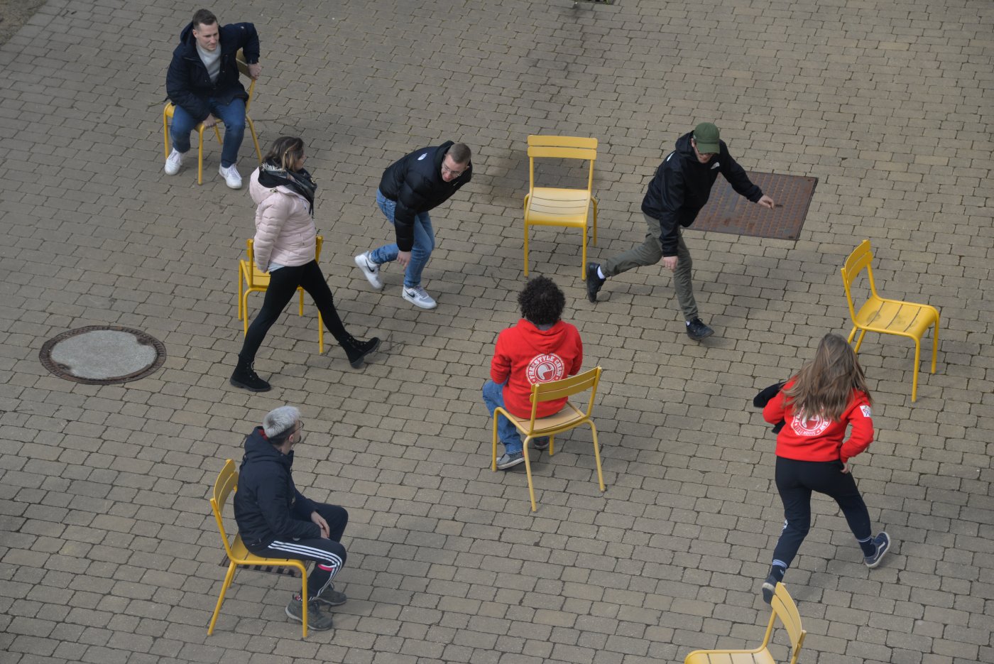 Image d'un groupe de jeunes qui fait une activité en groupe, bougeant d'une chaise à une autre.