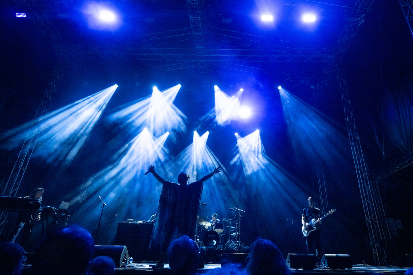 Image de la scène dans le noir avec des illuminations sur scène et un grand nombre de public devant la scène en train de regarder le concert