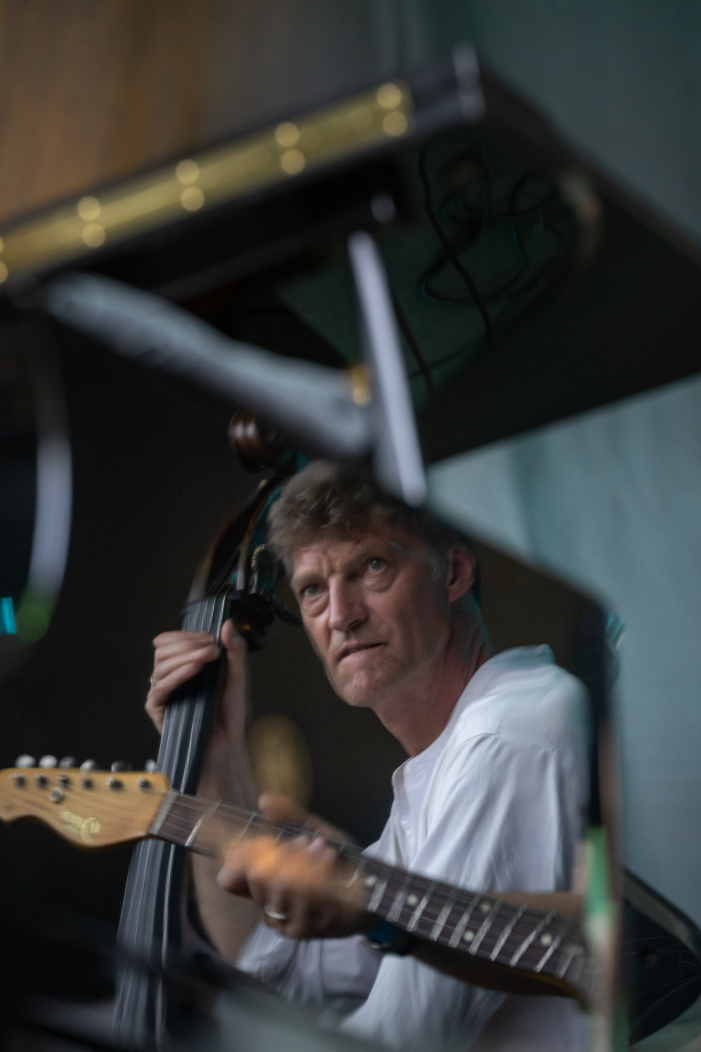 Image de la réflection d'un guitariste dans un miroir sur scène