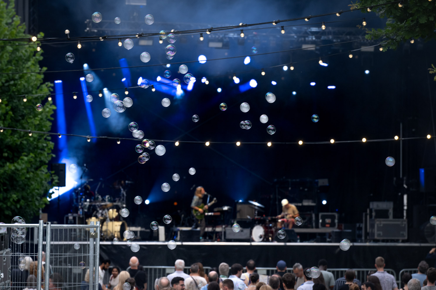 Image de la scène dans le noir avec des illuminations sur scène et un grand nombre de public devant la scène en train de regarder le concert