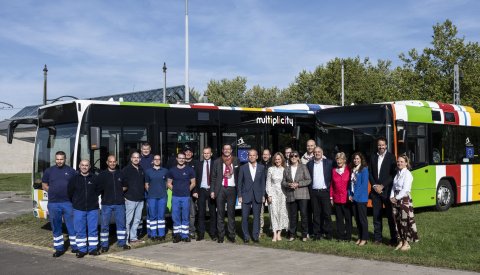 photode groupe avec des échevins devant deux bus
