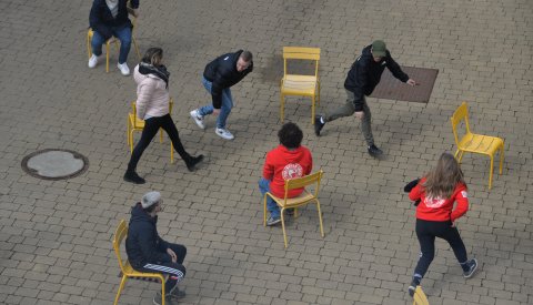 Image d'un groupe de jeunes qui fait une activité en groupe, bougeant d'une chaise à une autre.