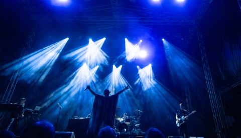 Image de la scène dans le noir avec des illuminations sur scène et un grand nombre de public devant la scène en train de regarder le concert